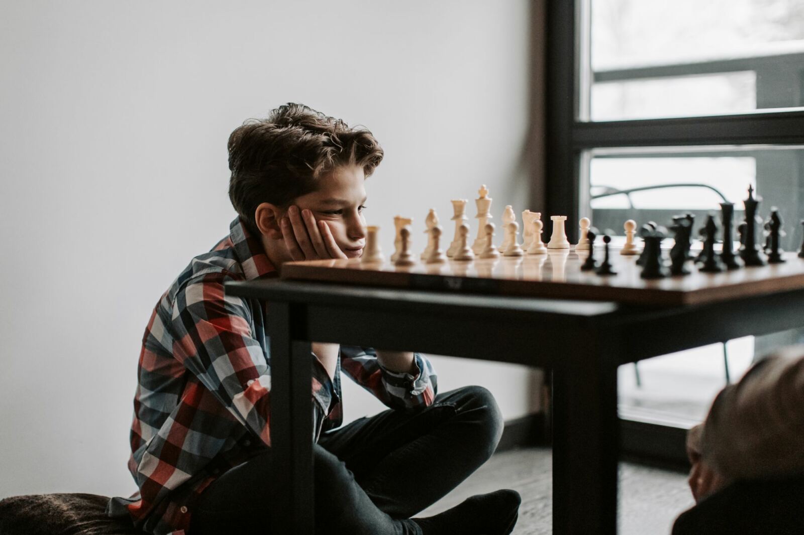 Adolescent qui réfléchit à son prochain coup devant un échiquier