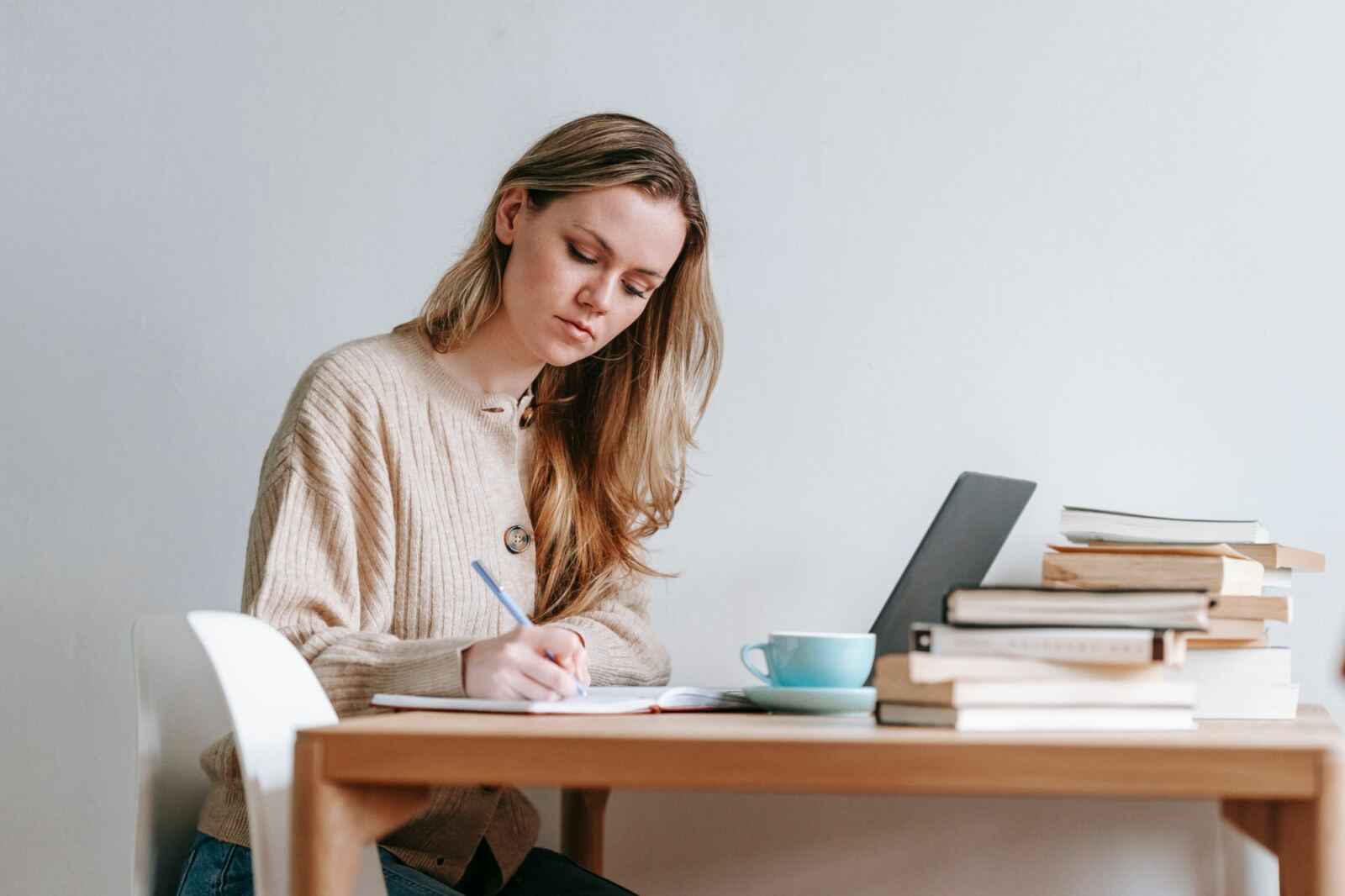 Femme prenant des notes à son bureau devant un ordinateur portable pendant une formation à distance