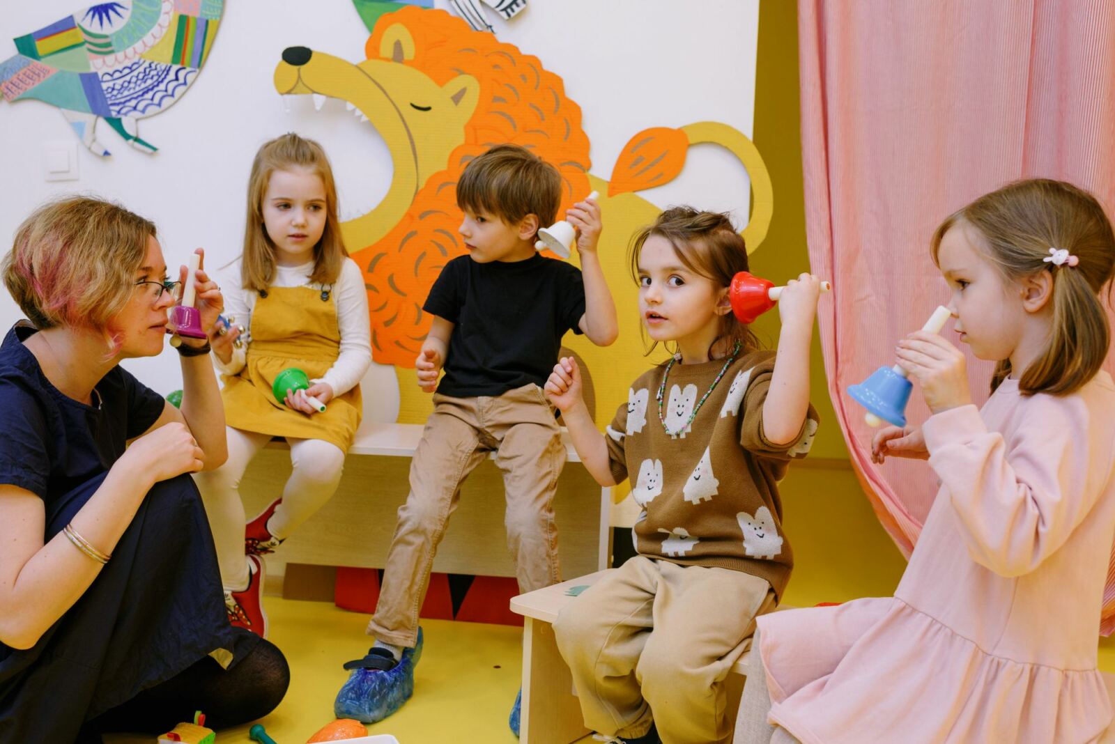 Enseignante et jeunes enfants jouant avec des clochettes de couleur pendant un atelier musical
