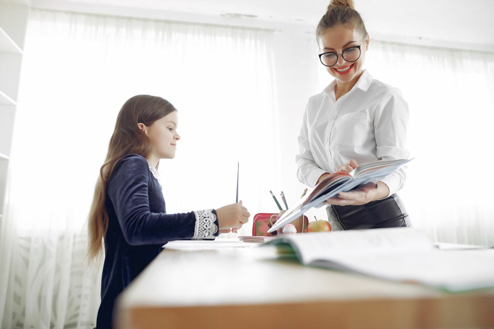 Élève montrant son travail à son enseignante, qui l'écoute expliquer sa démarche