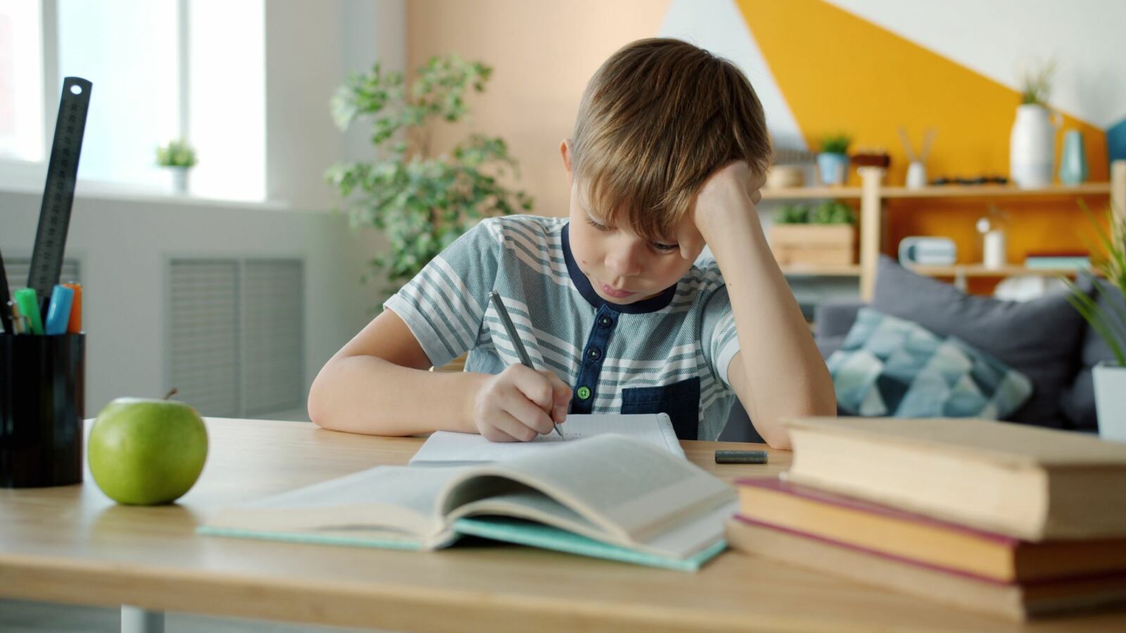 Élève fatigué, la tête appuyée sur la main, devant ses livres ouverts