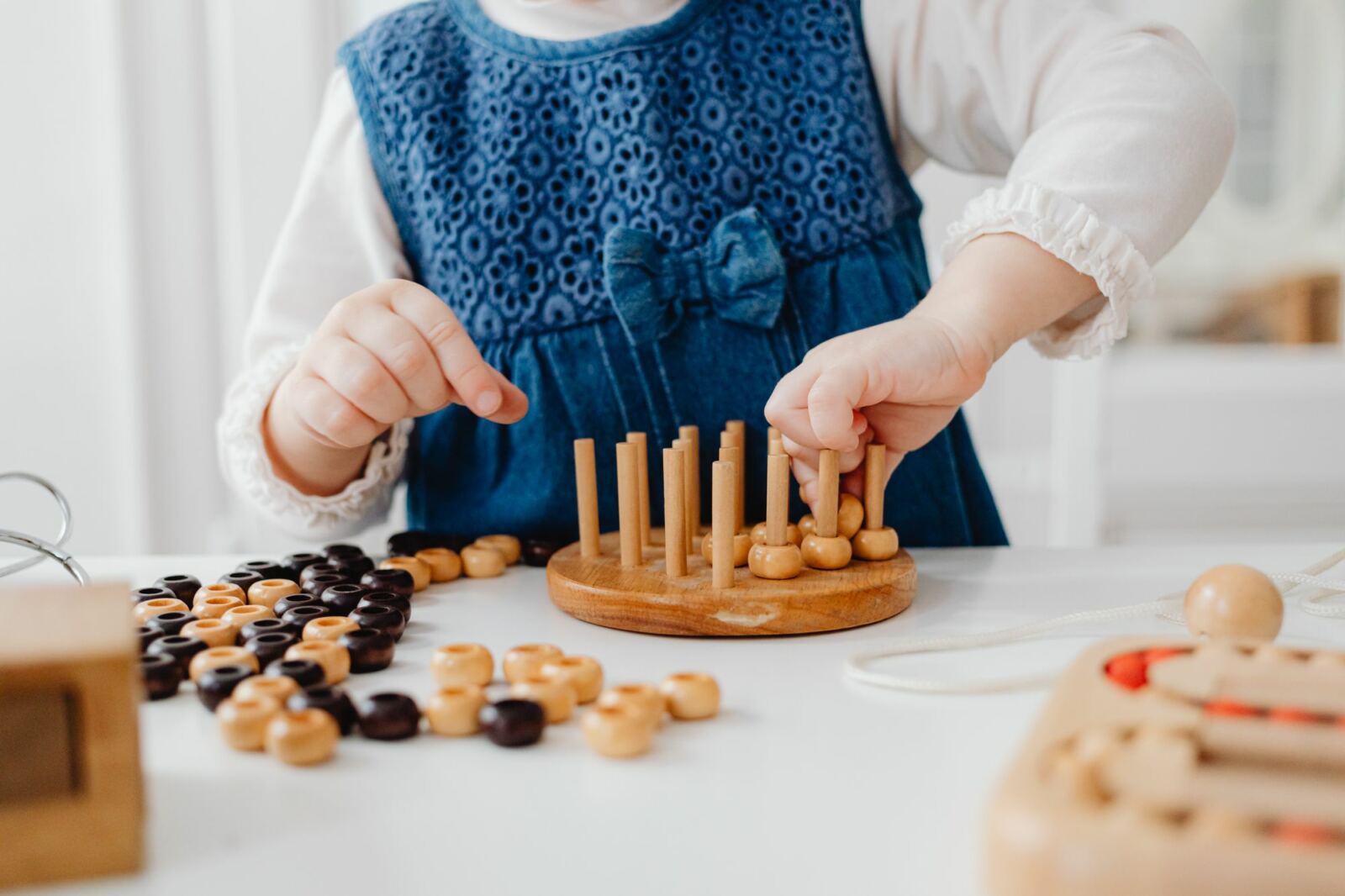 Enfant concentré qui empile des pièces de bois sur des tiges, activité d’attention et de tri
