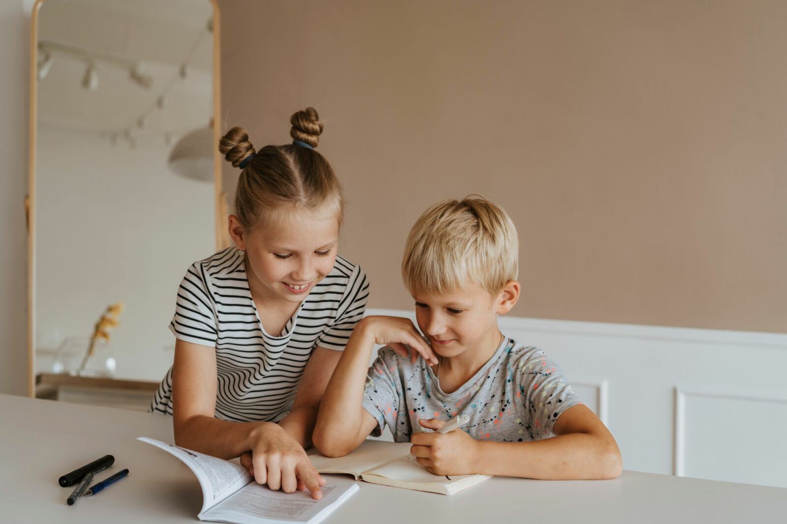 Une fillette aide son petit frère à lire, exemple d'entraide entre pairs