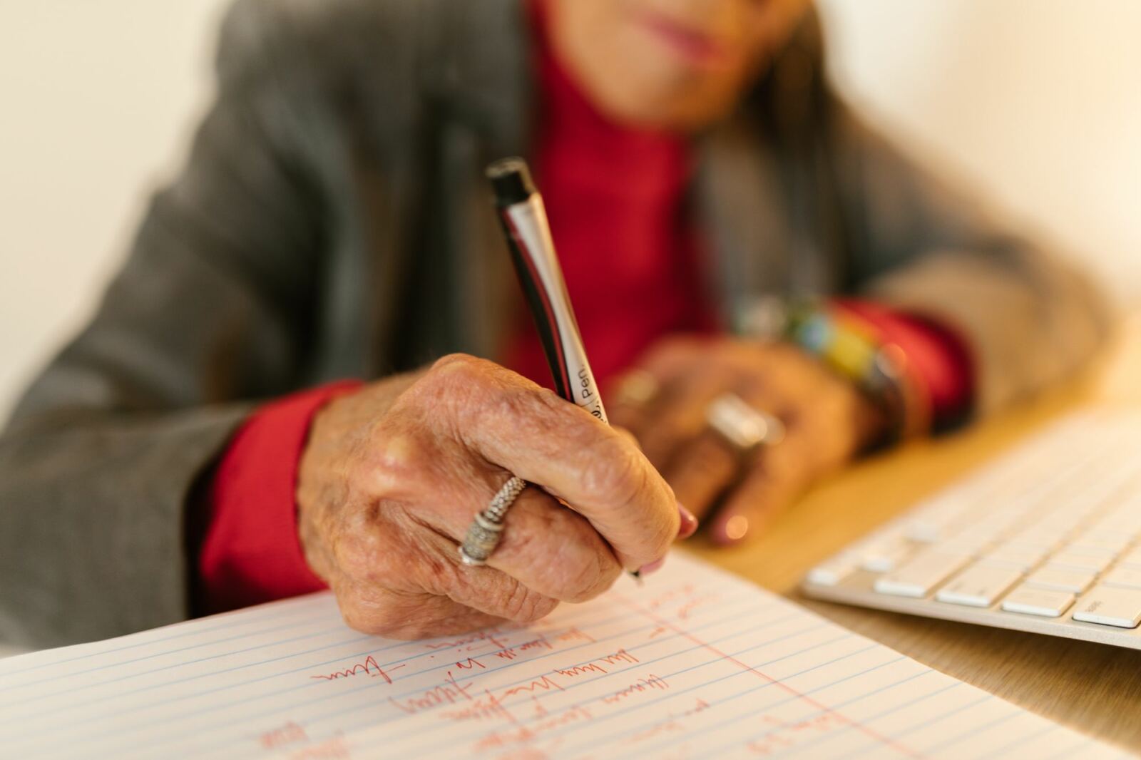 Main d'une personne âgée qui écrit au stylo sur une feuille, exercice de mémoire sur papier