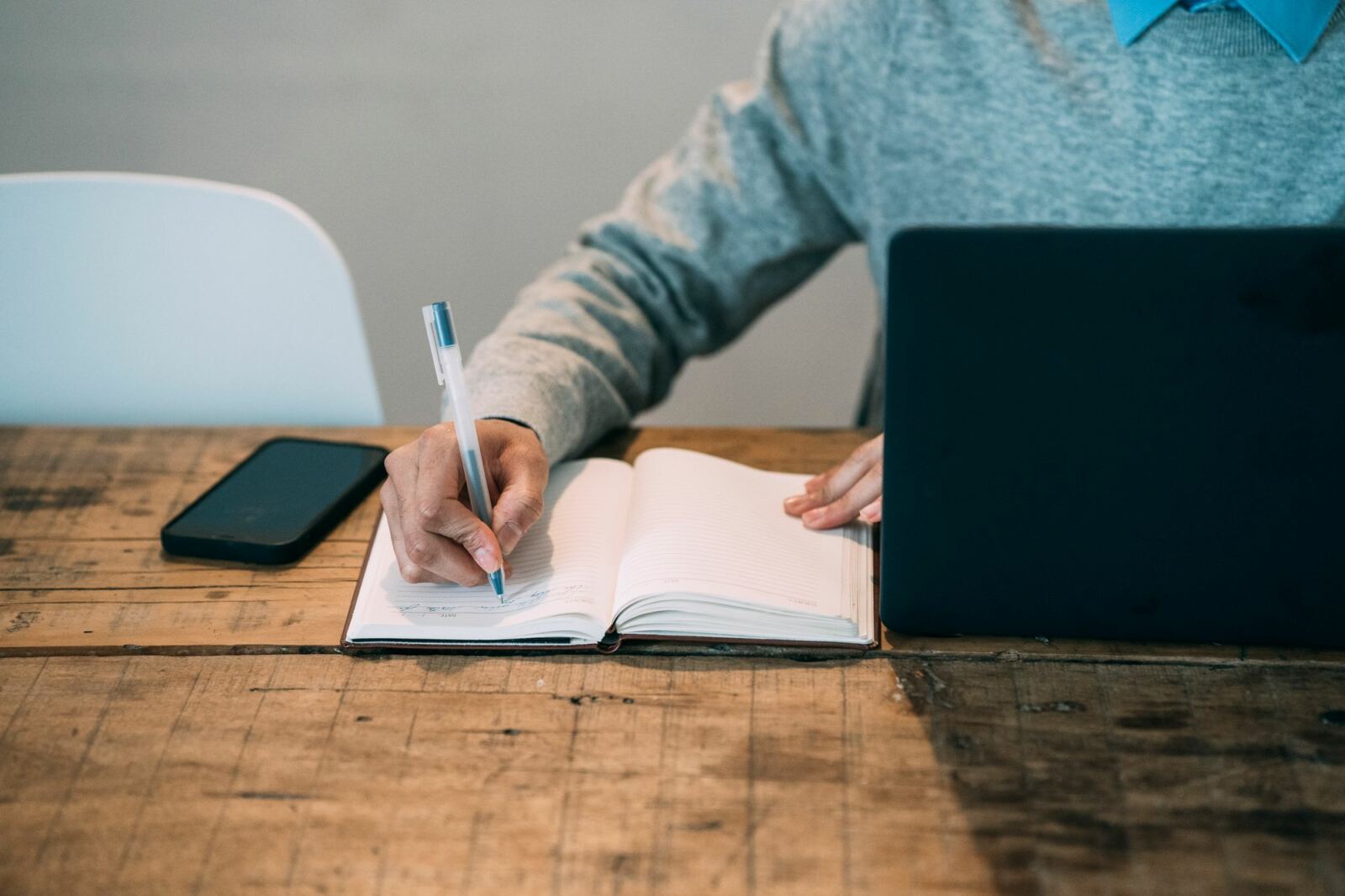 Professionnelle prenant des notes dans un carnet à côté d’un ordinateur portable, en formation à distance