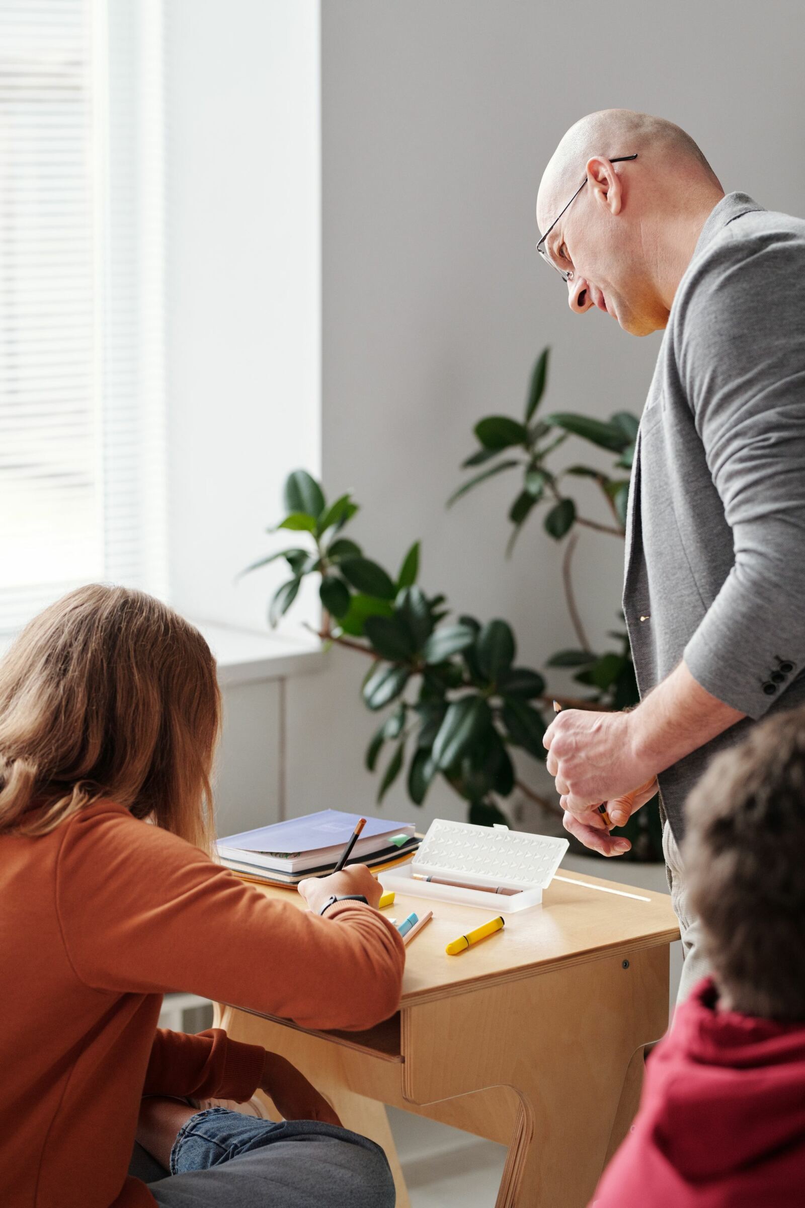 Enseignant penché sur le cahier d'une élève pendant la pratique guidée