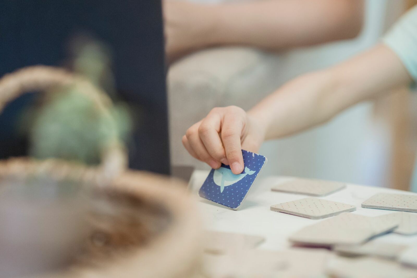 Main d’enfant posant une carte illustrée pendant un jeu de mémoire, support de manipulation en séance